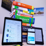 Elektronische Geräte vor einem Stapel Bücher.